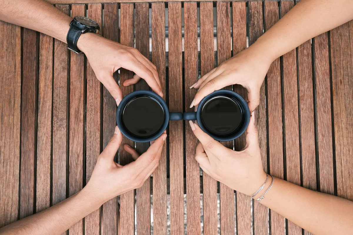 Hands holding a cup of black coffee